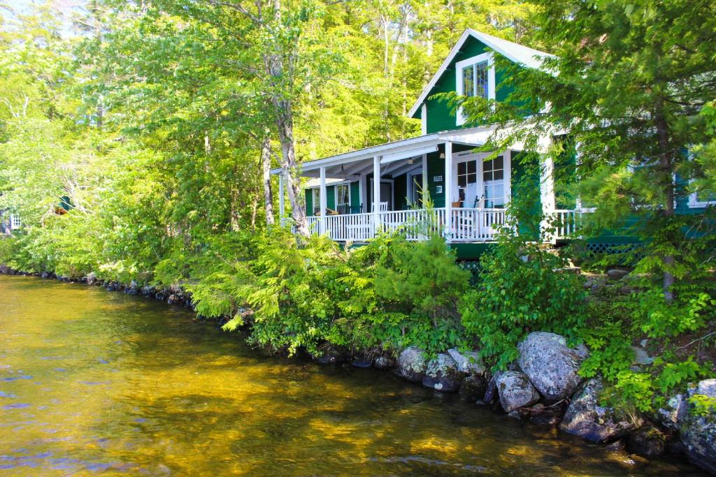 a green house on the side of a river at Cottage on Geneva Point in Moultonborough