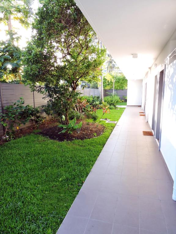 a walkway outside of a building with a green yard at Hotel Beaurivage in Noumea
