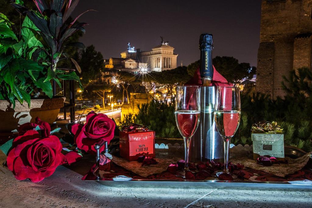 twee glazen wijn zittend op een dienblad met rozen bij Hotel Romano in Rome