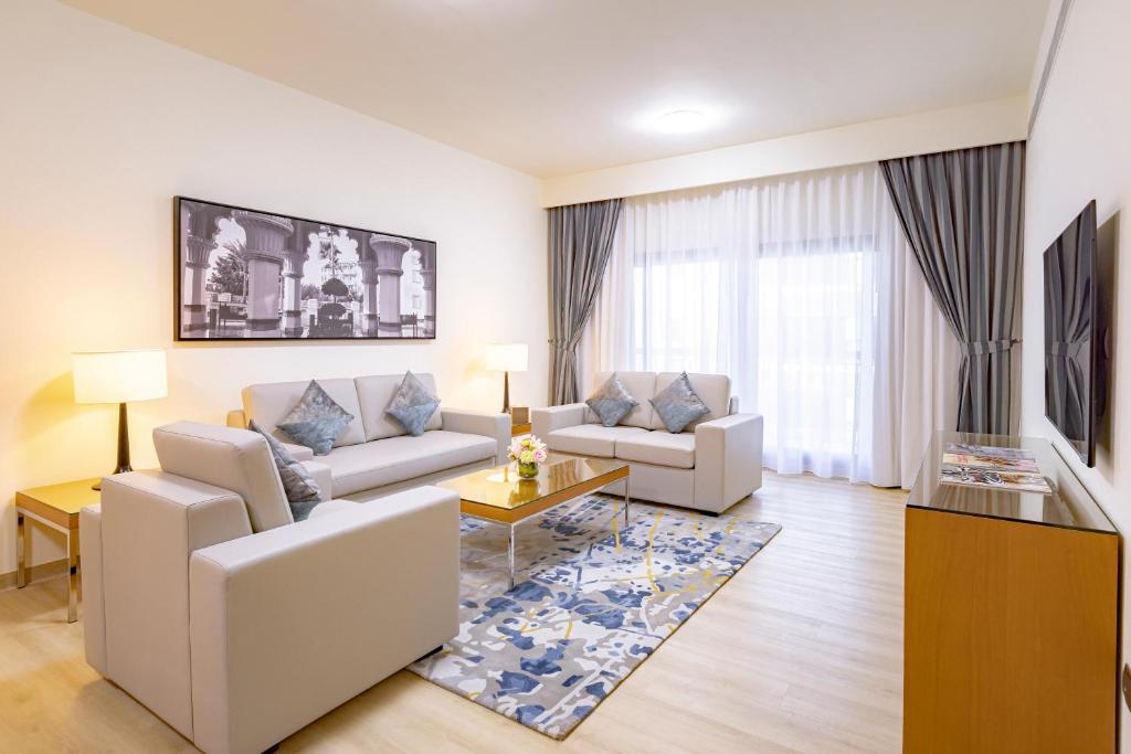 a living room with two couches and a table at Golden Sands Suites in Dubai