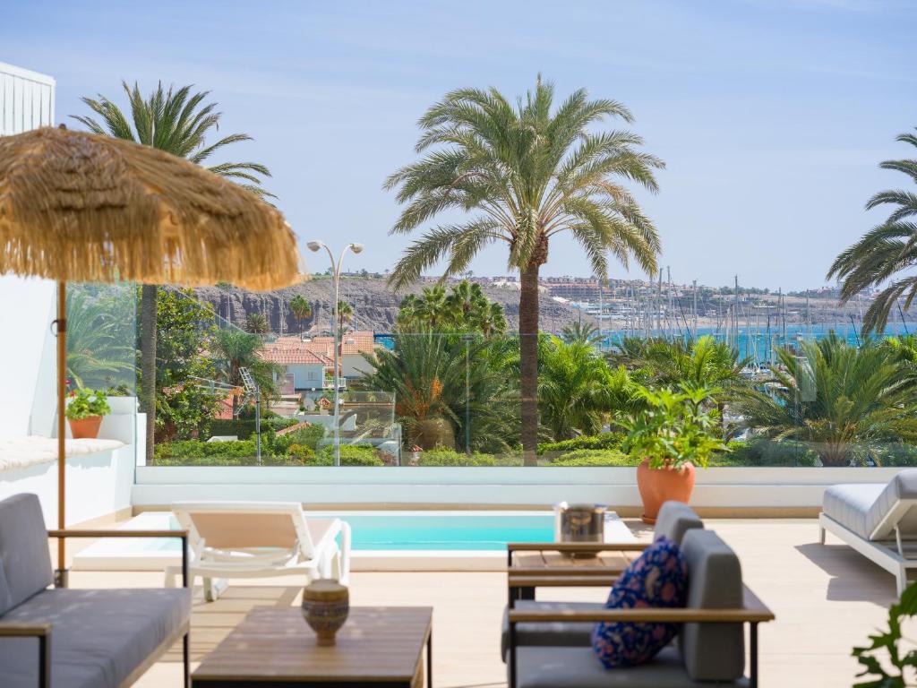 a living room with a pool and palm trees at Pasitoblanco Porto Mare 44 Seaview Villa private heated pool in Pasito Blanco