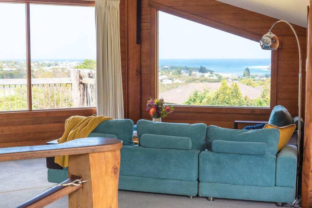 sala de estar con sofá azul y ventanas grandes en Pixies at Eco Bay, en Port Campbell