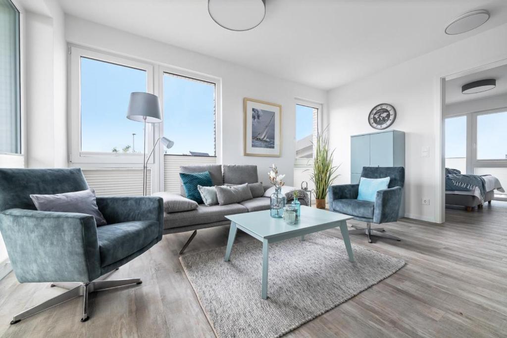 een woonkamer met een bank, 2 stoelen en een tafel bij BeachTerraceOne - EG, Meerblick, Terrasse, Kamin, Sauna in Olpenitz