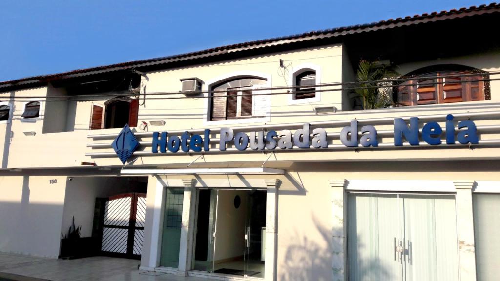 un edificio blanco con un cartel en el costado en Hotel Pousada da Néia, en Cananéia