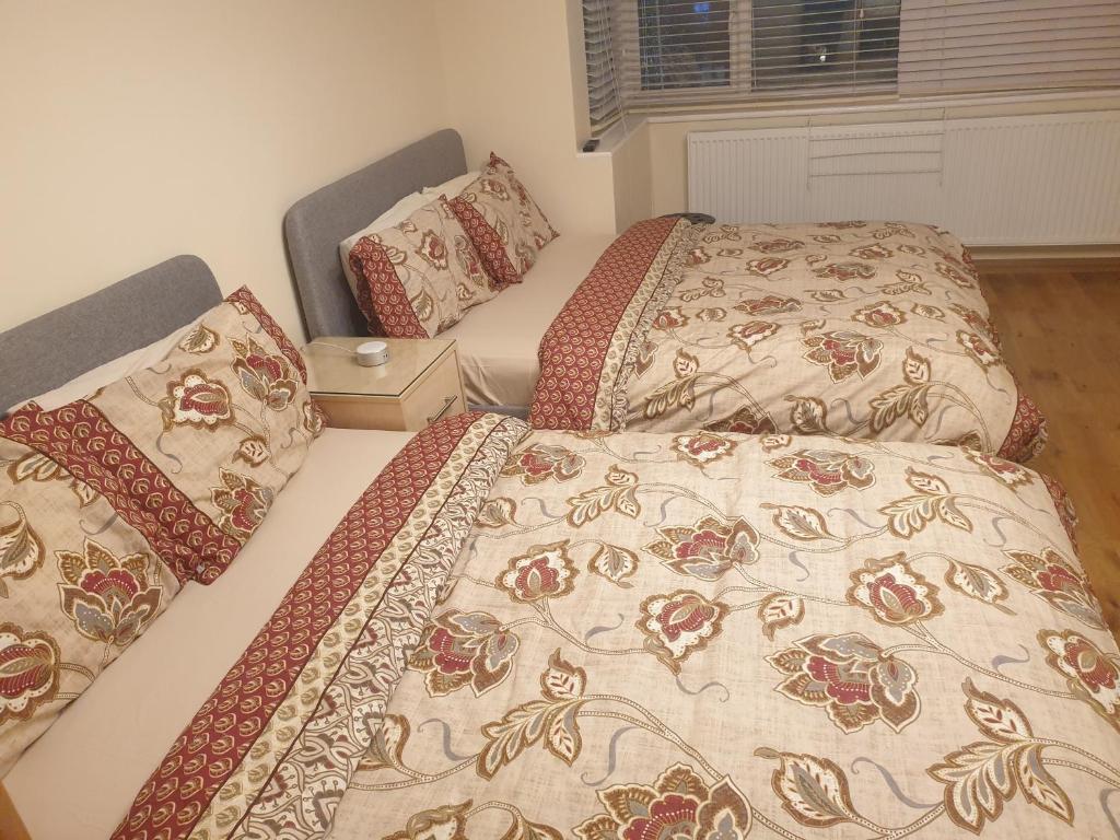 two beds sitting next to each other in a bedroom at London Luxury Apartment 3 Bed 1 minute walk from Redbridge Stn Free Parking in Wanstead