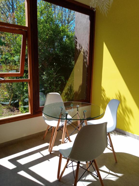 2 sillas y una mesa de cristal en una habitación con ventana en casita moderna frente al bosque en Mar del Plata