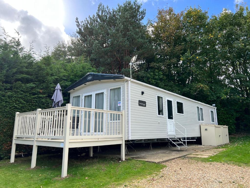 a white house with a porch and trees at 3 Bedroom Caravan MC34, Lower Hyde, Shanklin, Isle of Wight in Shanklin