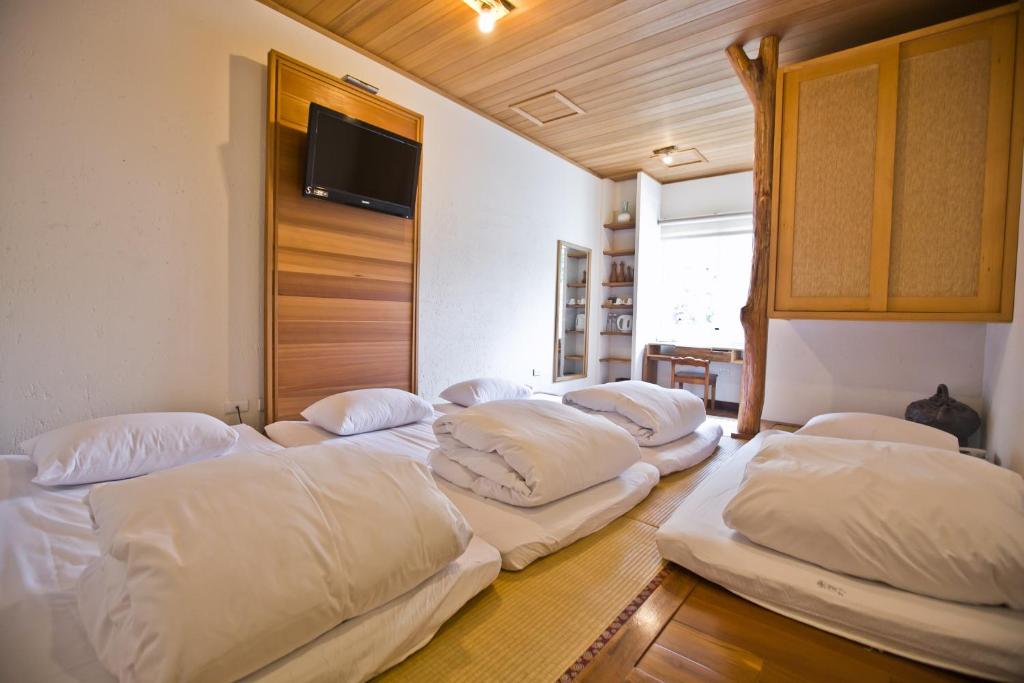 three beds in a room with a tv on the wall at 微笑58民宿 Smile 58 B&amp;B in Puli