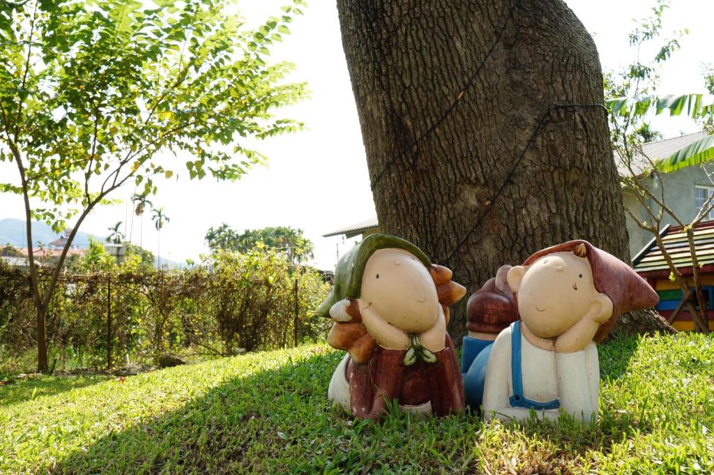 two statues sitting in the grass next to a tree at 微笑58民宿 Smile 58 B&amp;B in Puli