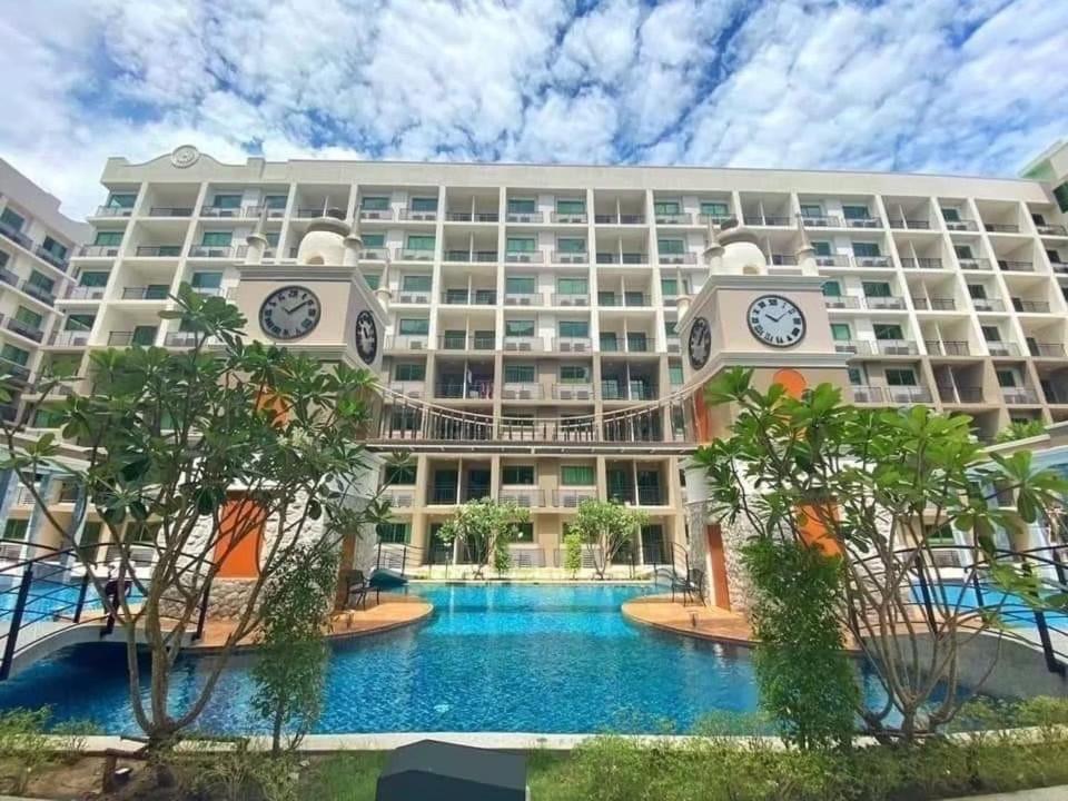 a large hotel with a swimming pool and clocks at Brand New 1Bdr Condo! 5 minutes from Famous Walking Street! in Pattaya South