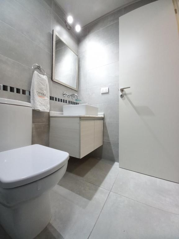 a bathroom with a toilet and a sink and a mirror at II Opera Towers Villa Carlos Paz in Villa Carlos Paz