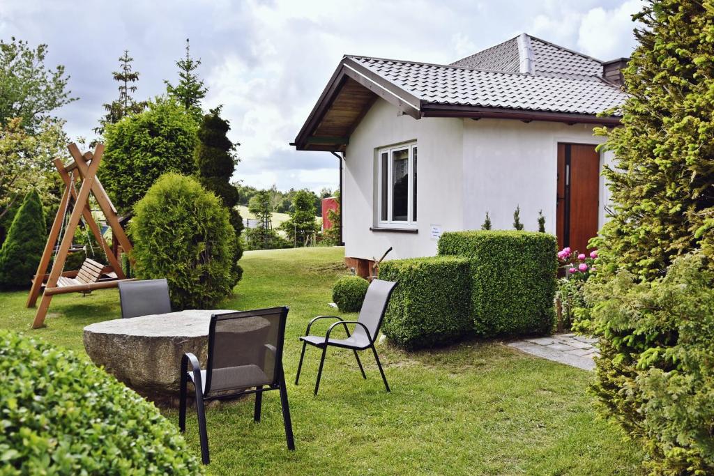 a small white house with a table and chairs in the yard at Wczasy u Gospodarza na Kaszubach in Kistowko