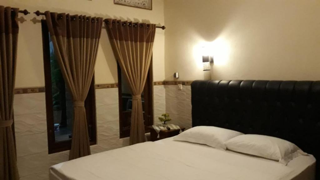 1 dormitorio con cama, espejo y cortinas en Jepun Inn, en Padangbai
