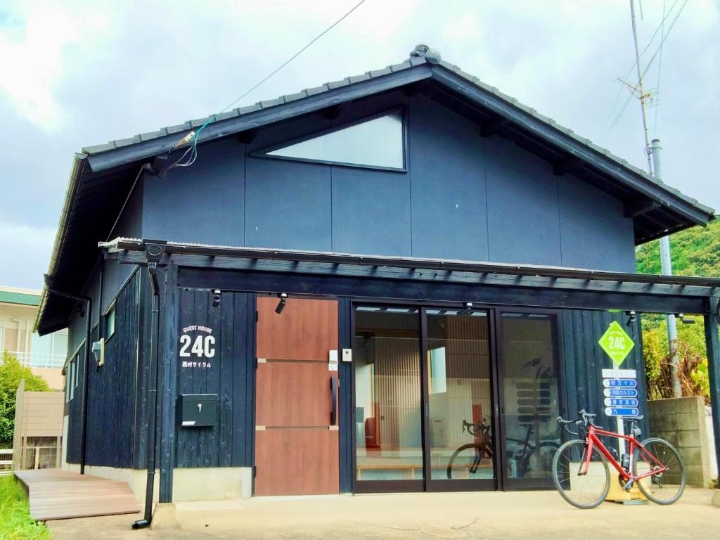 Izume的住宿－ゲストハウス 西村サイクル（24C），一座蓝色的建筑,前面有一辆自行车停放