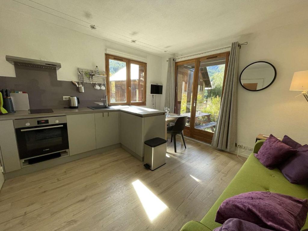 un salon avec un canapé vert et une cuisine dans l'établissement Appartement cosy à Serre-Chevalier, proche pistes, terrasse, parking, 2 étoiles, 2 pers. - FR-1-330E-127, à Saint-Chaffrey