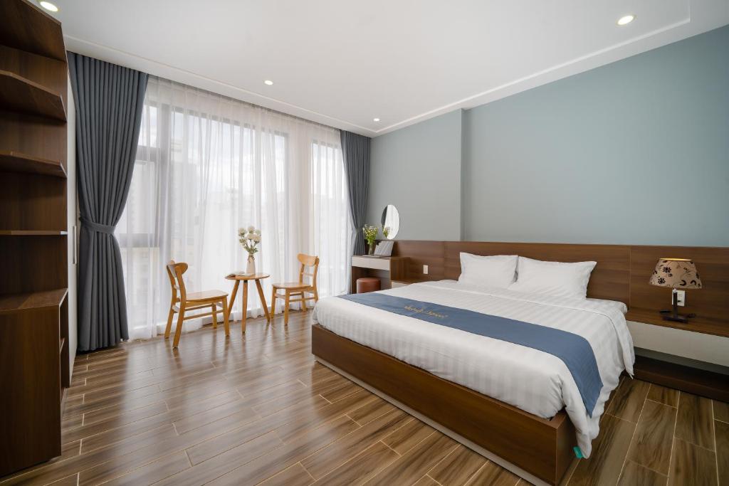 um quarto com uma cama, uma mesa e cadeiras em Melody Hotel em Da Nang