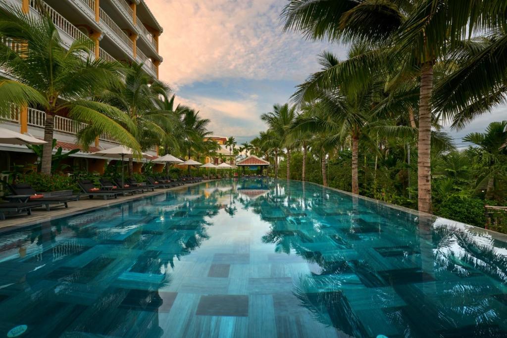 - une piscine dans un complexe avec des palmiers dans l'établissement La Siesta Hoi An Resort & Spa, à Hội An