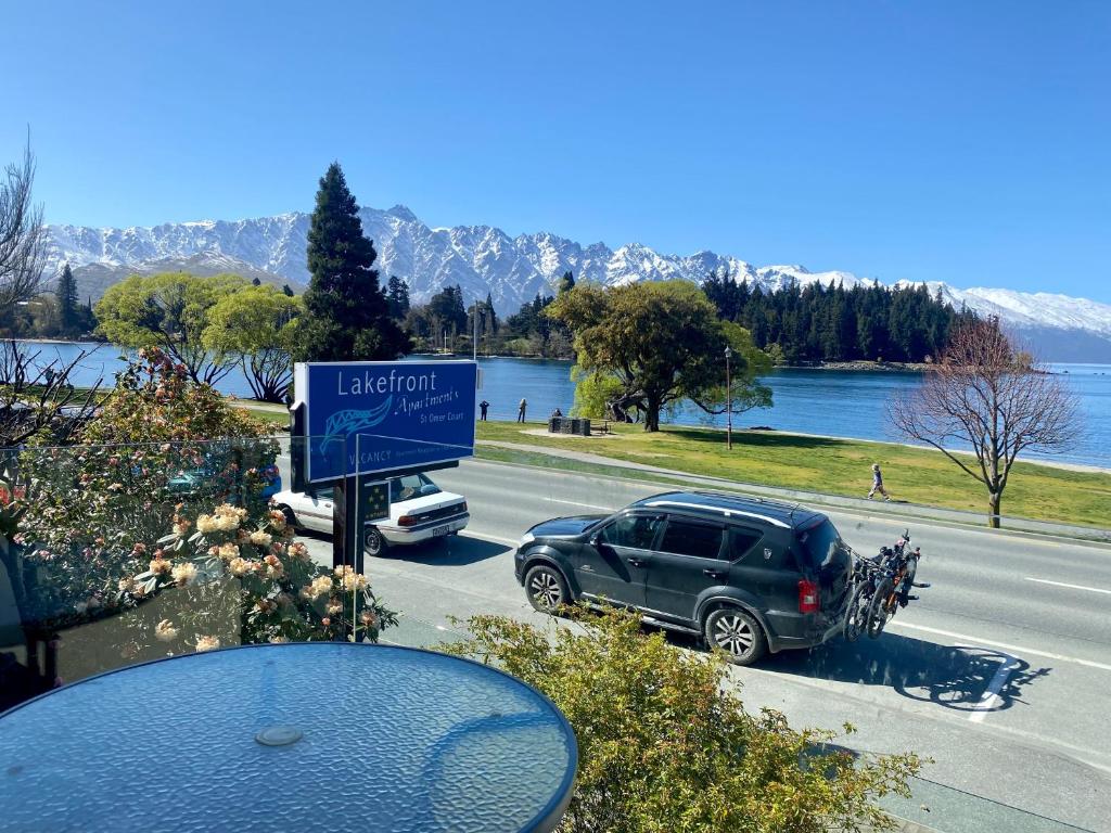 a car parked on a road next to a lake at Lakefront Gem, Absolute Waterfront in Queenstown