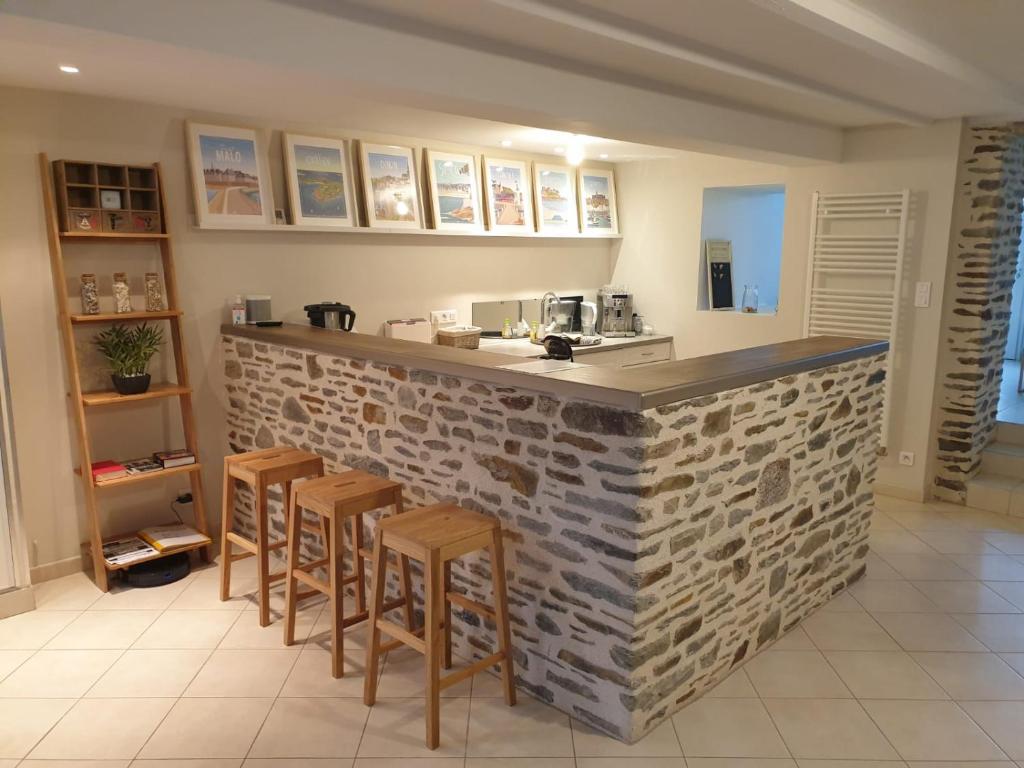 a kitchen with a stone bar with stools at Maison de ville située à 8 kms du Mont St Michel in Pontorson