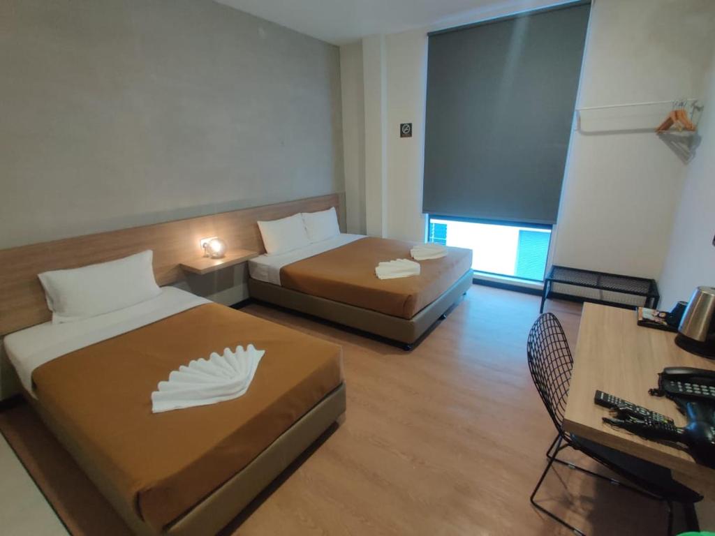 a room with two beds and a desk with a computer at Urban Inn, SP Saujana in Sungai Petani