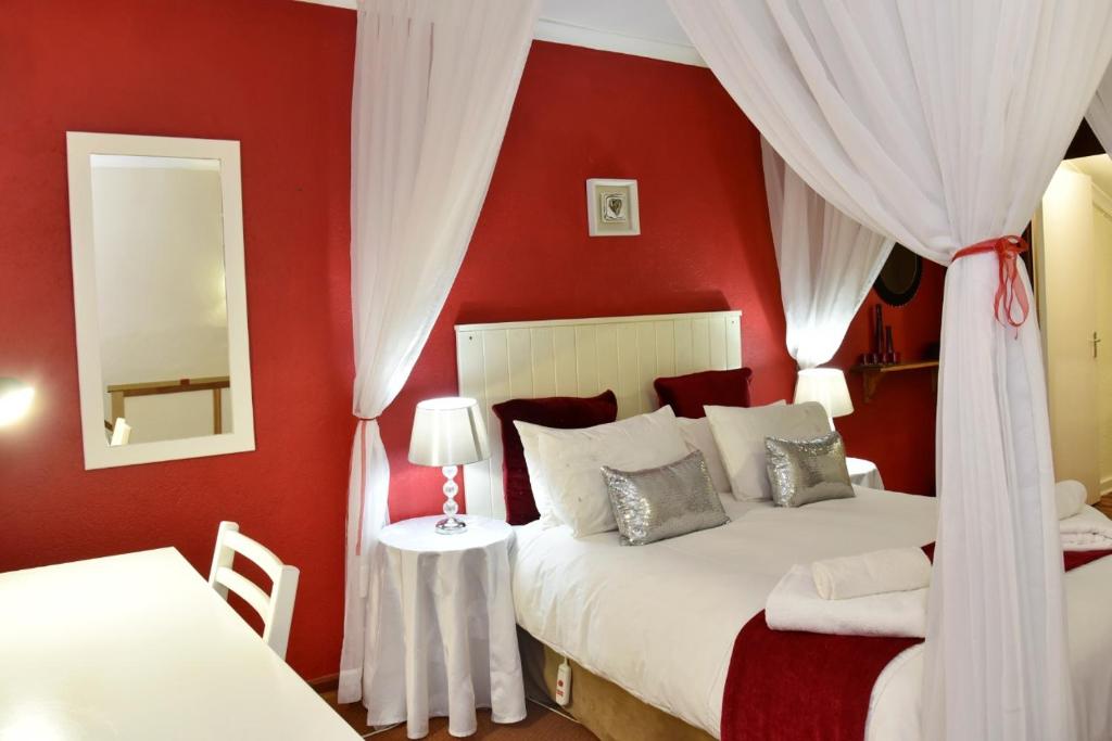 a red bedroom with two beds and a mirror at Villa Moria Romance in Dullstroom