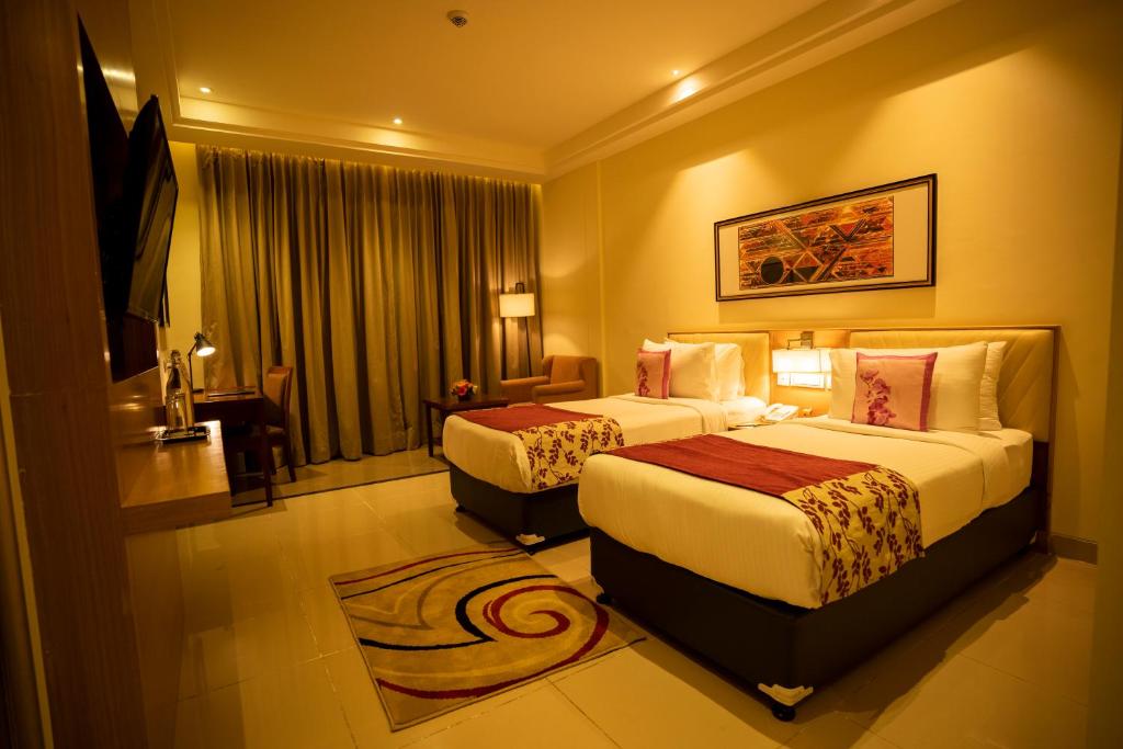 una habitación de hotel con dos camas y un sofá en Royal Orchid Central, Shimoga, en Shimoga