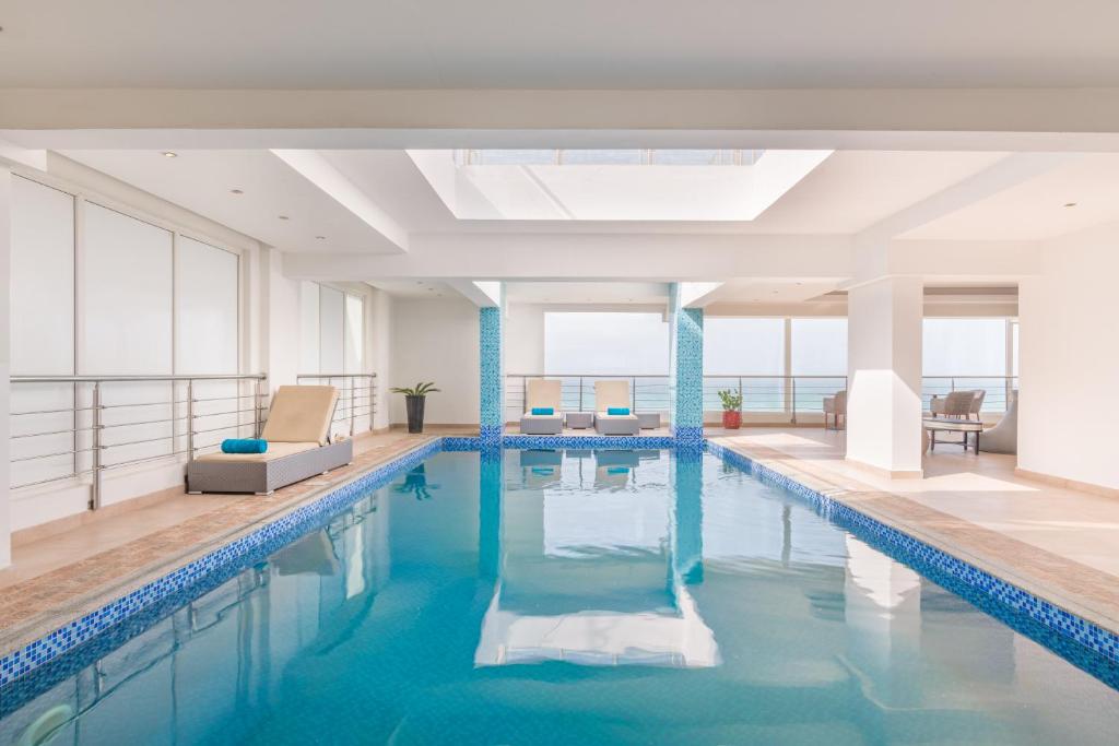 a large pool with blue water in a building at Al Hail Waves Hotel Managed By Centara in Seeb