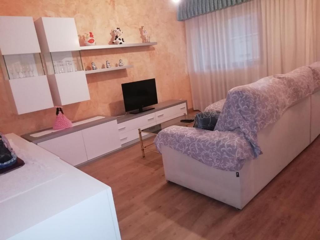 uma sala de estar com uma cadeira e uma televisão em Apartamento El Prado em Almazán