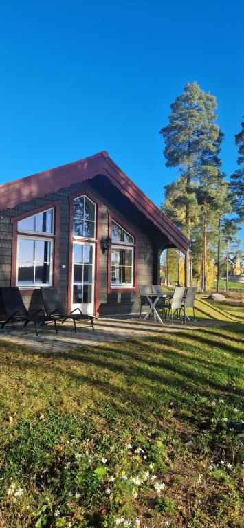 a house with a group of chairs in front of it at Lakeside log cabin Främby Udde Falun in Falun