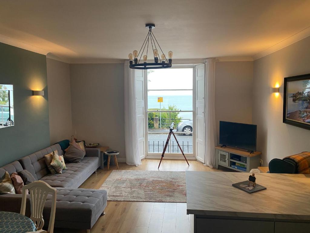 a living room with a couch and a tv at Newton Croft Tenby overlooking North Beach in Tenby