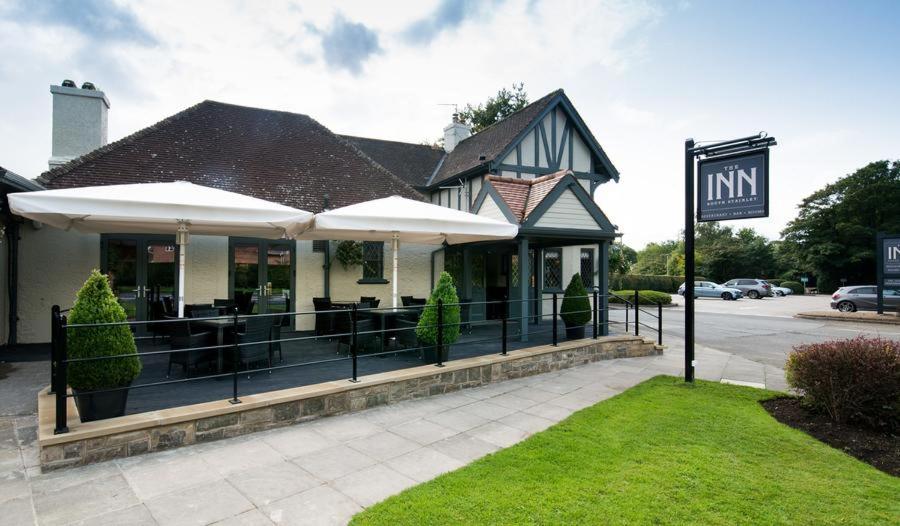 a restaurant with umbrellas in front of a building at The Inn South Stainley in Harrogate