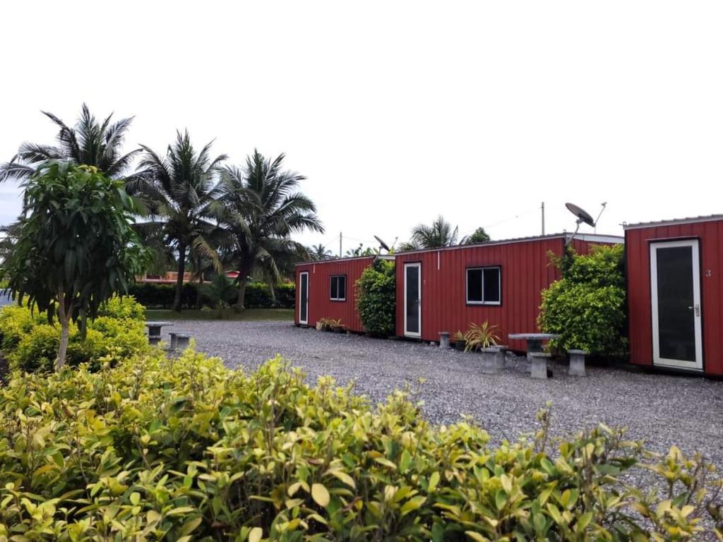 a row of red buildings with trees and bushes at AsiaCamp - Cabin Sungai Sireh in Tanjung Karang