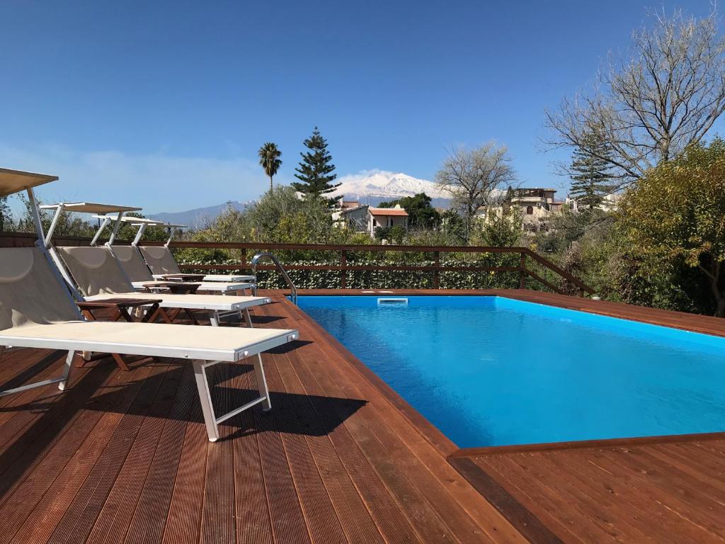 una piscina en una terraza con mesas y sillas en John Sea Suites en Giardini Naxos