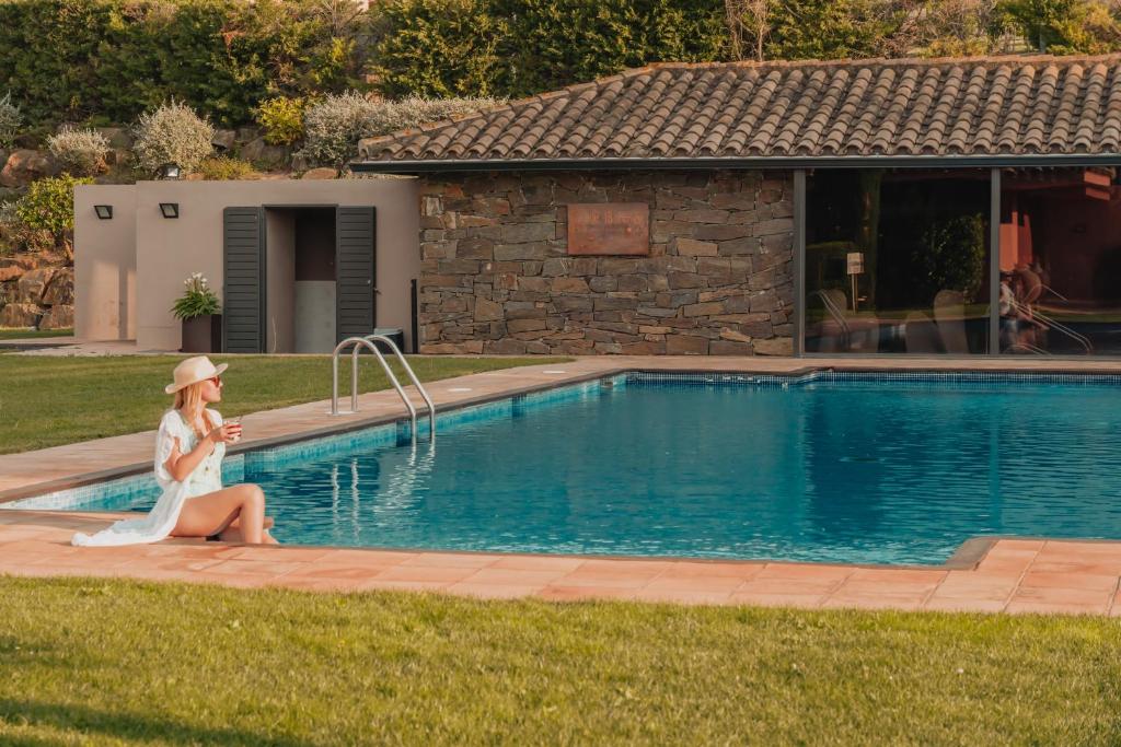 una mujer sentada junto a una piscina en Hotel TorreMirona Golf & Spa, en Navata