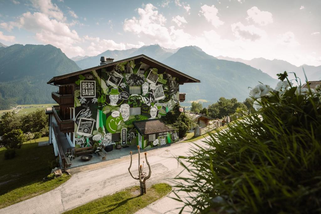 ein mit Graffiti bedecktes Gebäude mit Bergen im Hintergrund in der Unterkunft BergBaur in Neukirchen am Großvenediger