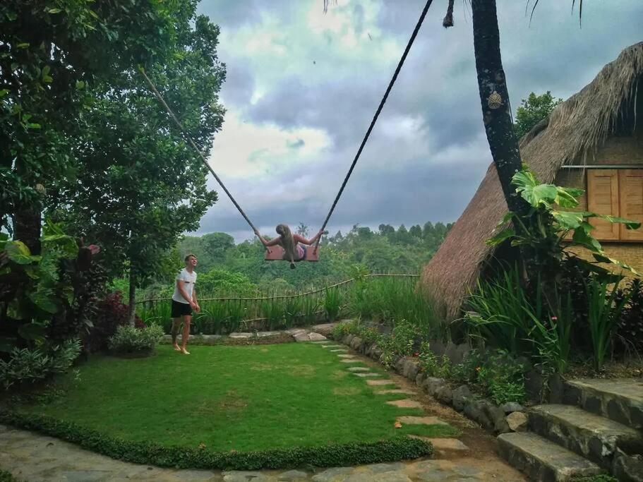 Eine Frau sitzt in einer Schaukel im Garten in der Unterkunft Eco Hut by Valley and 7 Waterfalls in Ambengan