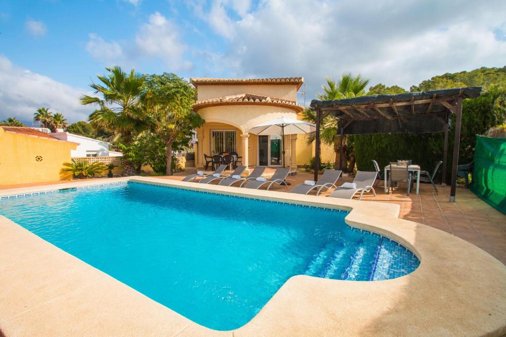 una piscina con sillas y una casa en Villa La Martina - PlusHolidays, en Calpe