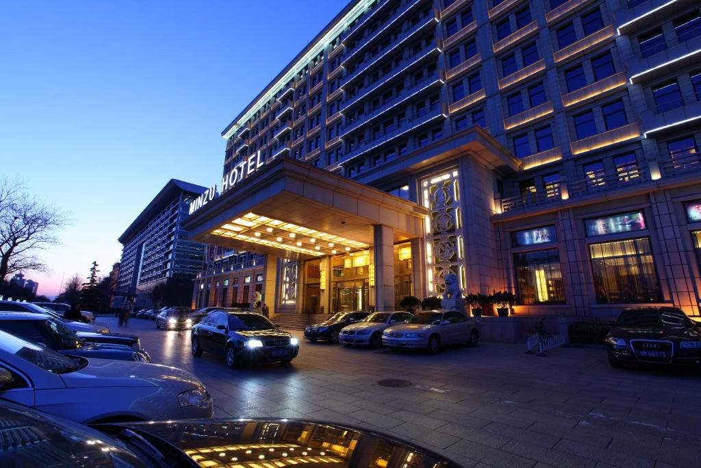 un estacionamiento con autos estacionados frente a un edificio en Min Zu Hotel, en Beijing