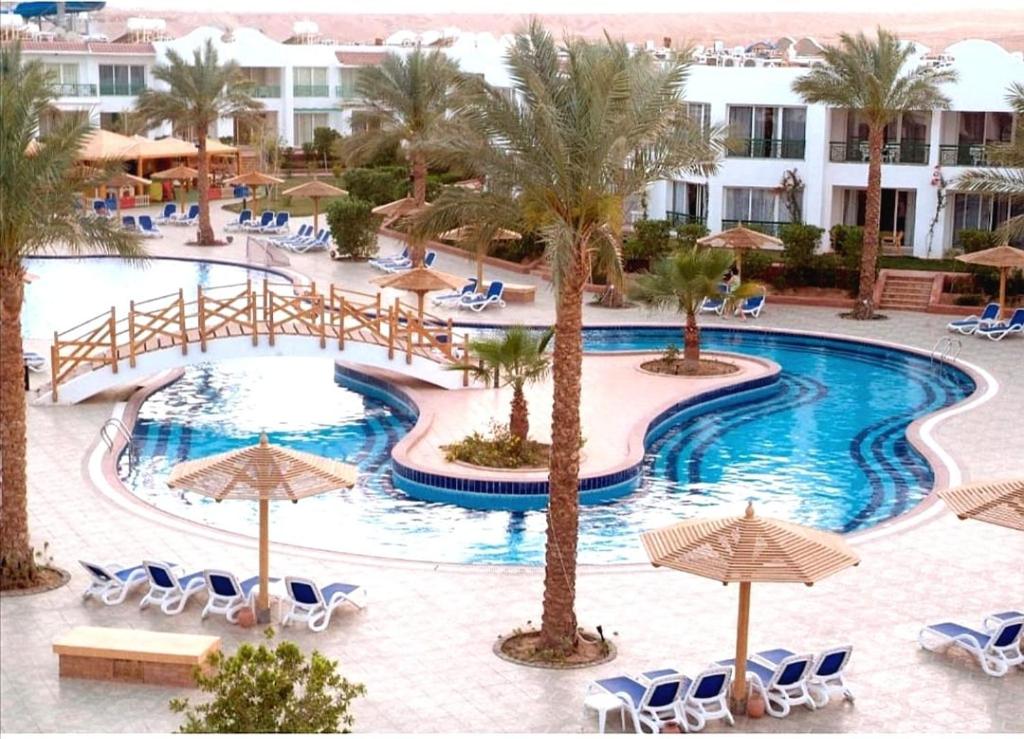 a pool at a resort with chairs and umbrellas at chalet Naama bay Heights in Sharm El Sheikh