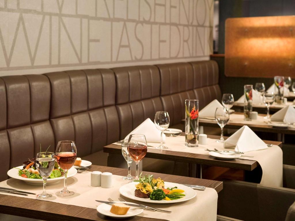 un restaurante con dos mesas con copas de vino en Novotel Düsseldorf City West, en Düsseldorf