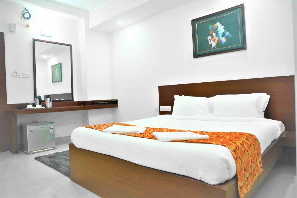 een slaapkamer met een groot bed en een spiegel bij Harekrishna Hotel & Restaurant in Bhubaneshwar