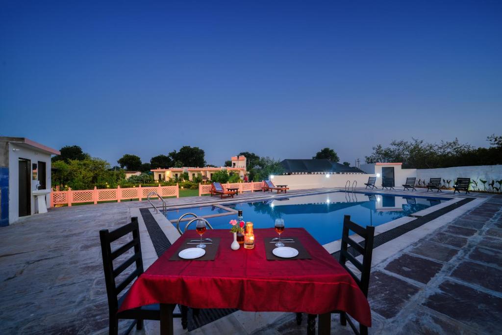 a table with a red table cloth sitting next to a pool at Ranthambore Nature Camp Resort in Sawāi Mādhopur