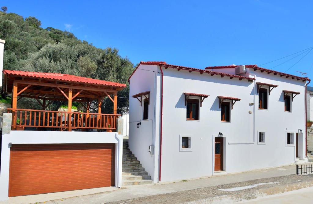 Casa blanca con garaje marrón en Plokamos House, en Plokamianá