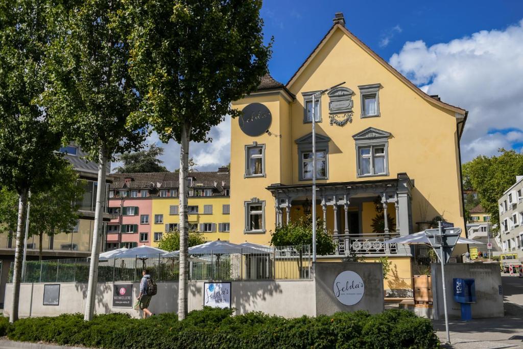 ein gelbes Gebäude mit Sonnenschirmen davor in der Unterkunft Selda's in Schaffhausen
