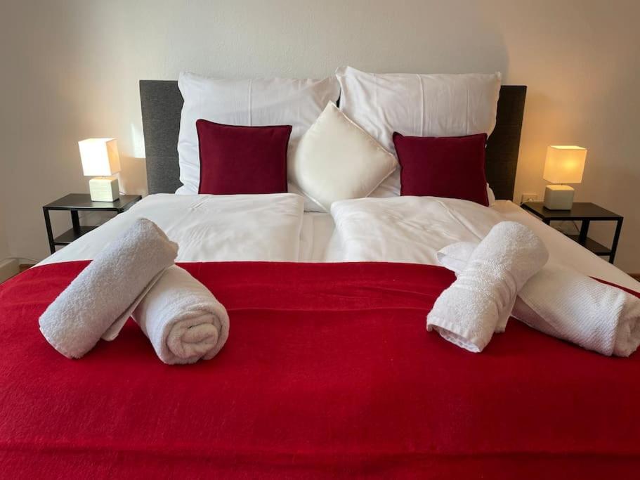 a large bed with two towels on a red blanket at Black Forest Apartment in Baden-Baden