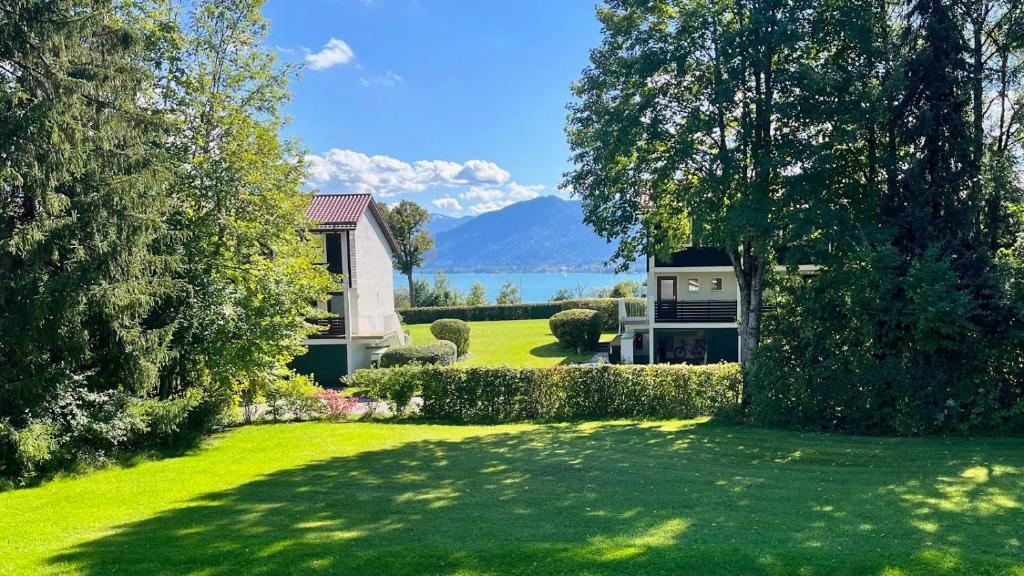 a house with a green yard with a view of the water at Apartment Kaltenbrunn Serviced Apt mit Seeblick am Tegernsee Business & Long Stay only in Gmund am Tegernsee