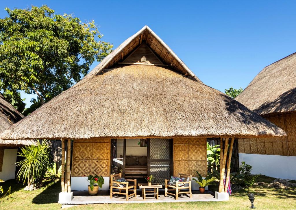 a hut with chairs and a thatched roof at Three Little Birds Resort in Anda