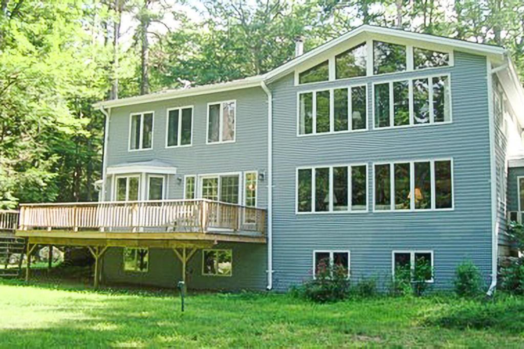 una grande casa blu con portico e terrazza di Alton Bay Beach House a Alton Bay