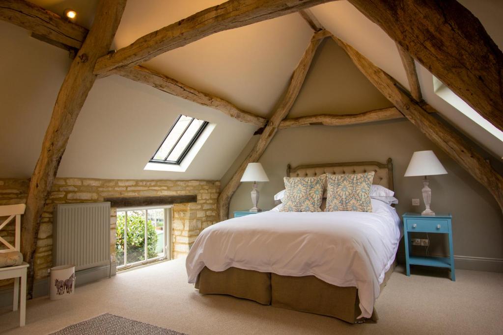 a bedroom with a large bed with exposed beams at The Potting Shed, 5* Luxury escape Cirencester in Cirencester