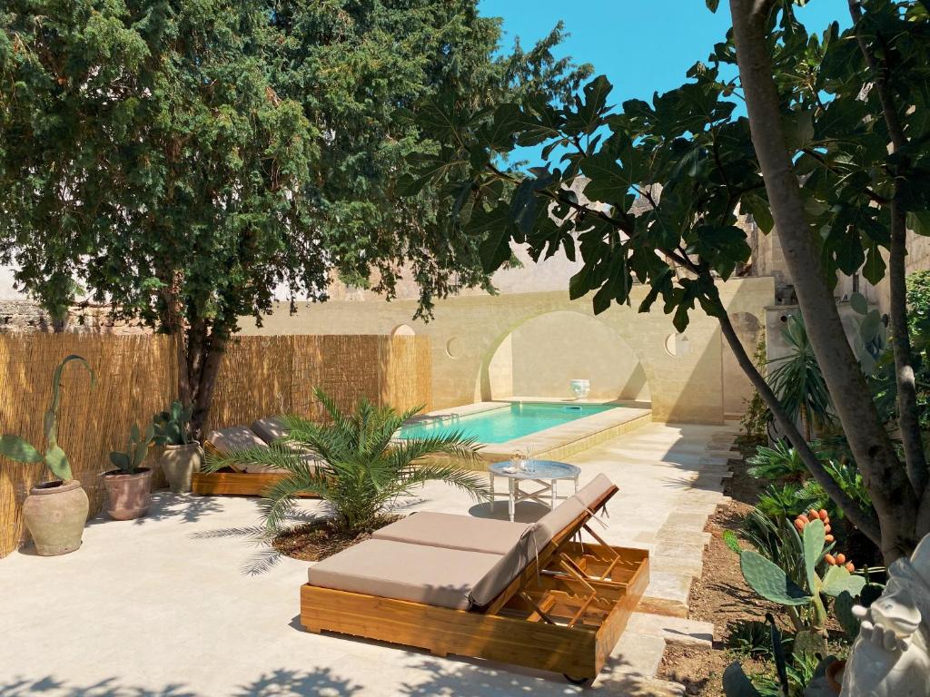 une piscine avec un banc, une table et des arbres dans l'établissement Palazzo Giustiniani L'Ambasciatore, à Sogliano Cavour